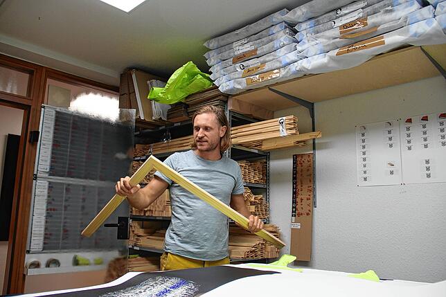 In der kleinen Werkstatt rahmen er und seine Mitarbeiter die Fotodrucke.