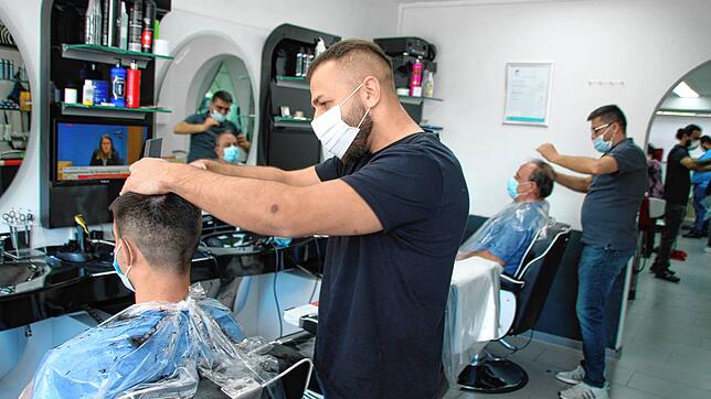 Ramazan Duchi (vorne) und Kurtbey Burunsuz vom Salon Aydo müssen ihre Kunden mit Mundschutz bedienen.