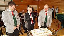 Neben Dirigent Matthias Fink (von links) und Bürgermeister Jochen Spieß schneidet Patrick Holl, Vorsitzender der Musikkapelle Ablach, ...