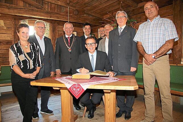 Eintrag ins Goldene Buch der Stadt Triberg: Landrat Sven Hinterseh (sitzend) erfüllt den Wunsch bei seinem Besuch im Rathaus gerne, ...