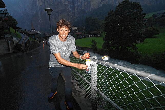 Bergläufer Benedikt Hoffmann auf der Strecke des Jungfrau-Marathons am Abend vor dem Rennen. Er bringt im strömenden Regen Flaschen an, ...