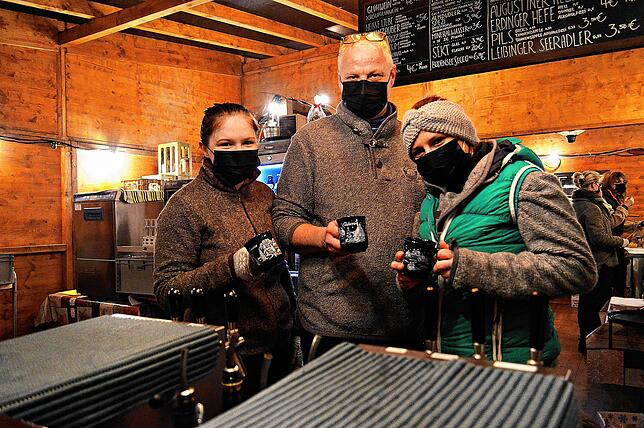 Lena Falkenberg, Wolfgang Merk und Sophia Mendez (von links) schenken an der Überlinger Eisbahn Glühwein, Punsch und weitere Getränke aus.