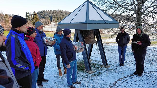 Pfarrer Bernhard Stahlberger (rechts) segnet die neue Glocke auf dem Schellenberg, die anschließend an die Dorfgemeinschaft übergeben wird.