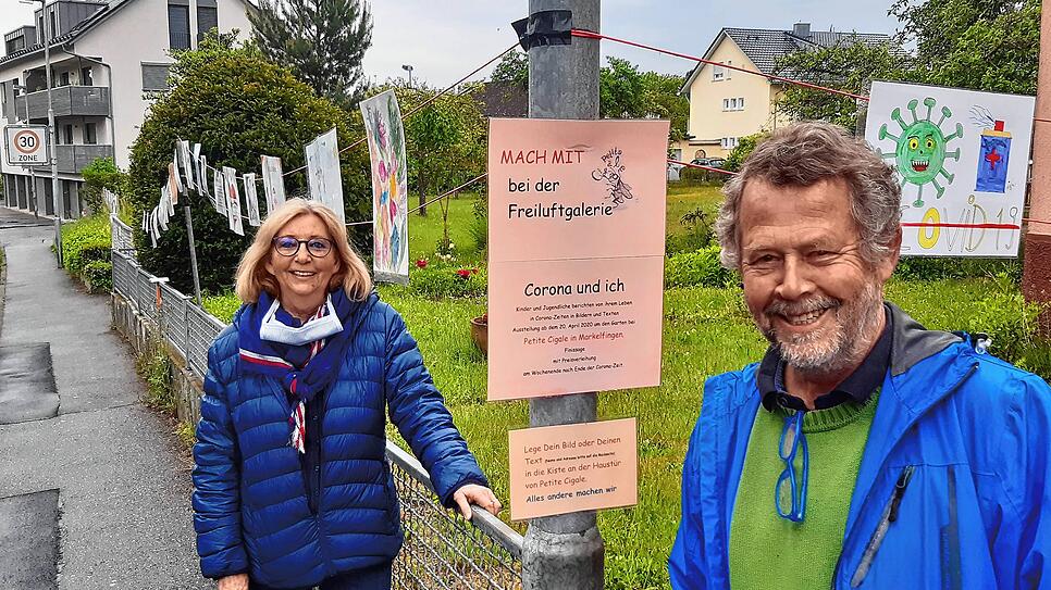 Charlotte Villinger-Ménétré und Hans-Georg Lauer vom Team Petite Cigale vor den Bildern der Freiluftgalerie „Corona und ich“ ...