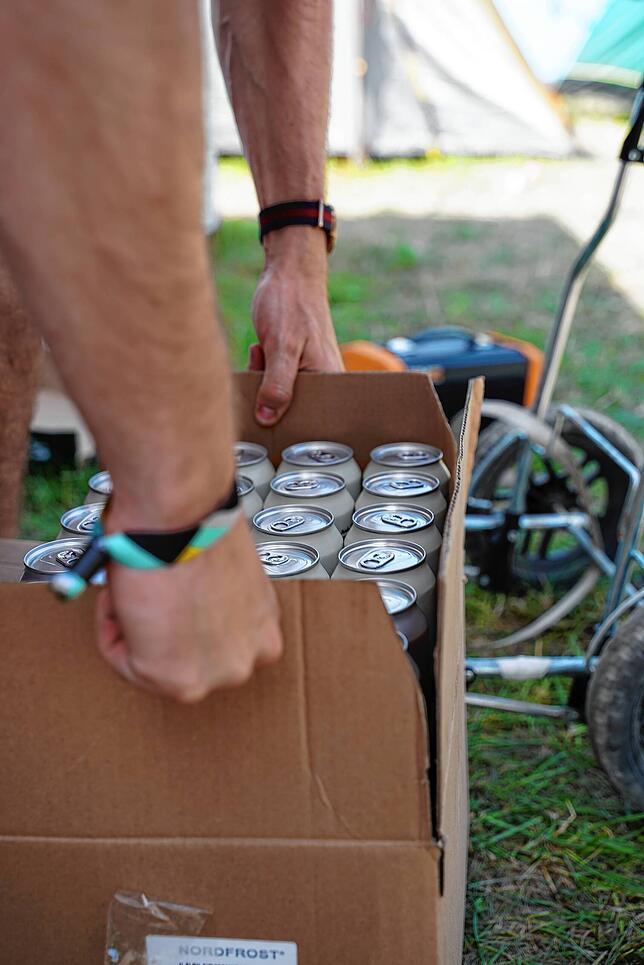 Nicht nur Wasser wird bei den Temperaturen konsumiert: Ein Besucher transportiert eine frisch gekaufte Palette Dosenbier zum Zelt.