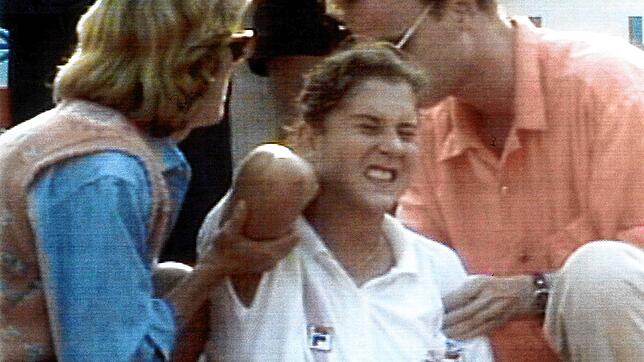 Die damals 19-jährige Monica Seles (M.) sitzt am 30. April 1993 unter Schock und mit Schmerzen auf dem Court. Kurz zuvor wurde ihr mit ...