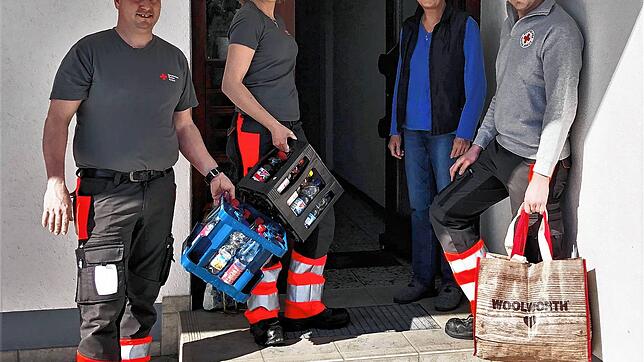Helfer des DRK liefern Einkäufe an einer Haustür ab. Jetzt wird die Aktion vorläufig eingestellt. Bild: Peter Koch