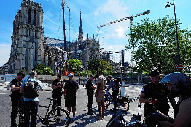 Polizisten kontrollieren vor der Kathedrale Notre-Dame in Paris Personen an der für die Olympischen Spiele eingerichteten ...