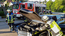 Die Feuerwehr inspiziert den Motorraum des Fahrzeugs, dessen Fahrer Rauchentwicklung festgestellt hat.