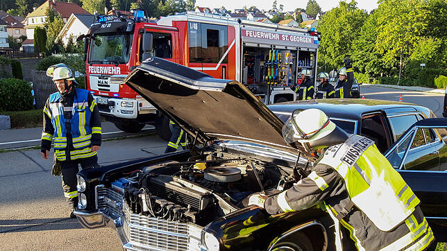 Die Feuerwehr inspiziert den Motorraum des Fahrzeugs, dessen Fahrer Rauchentwicklung festgestellt hat.