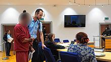 Ein Justizbeamter führt den Angeklagten (links) in den Saal am Landgericht Waldshut-Tiengen im Prozess um eine Tankstellen-Messerattacke.
