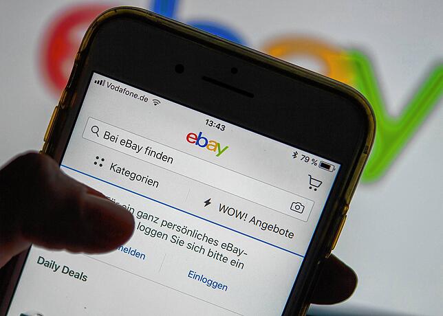 Eine Frau hält ein Smartphone mit der geöffneten ebay-App in der Hand (gestellte Szene). Gerade in Kleinanzeigen im Netz tummeln sich ...