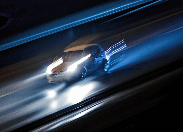 Ein Fahrzeug braust über eine Autobahn. Die Aufnahme erfolgte mit Langzeitbelichtung und Mitzieh-Effekt.