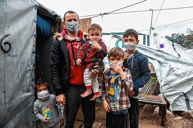 Eine Flüchtlingsfamilie in dem Lager in Moria, auf der griechischen Insel Lesbos, trägt Masken zum Schutz gegen das Virus.