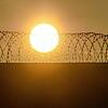 Die Sonne geht über der Mauer einer Justizvollzugsanstalt auf.