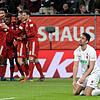 Augsburgs Rani Khedira (r) kniet auf dem Rasen, während die Spieler von München über das 2:3 jubeln.