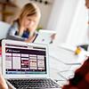 Eine Lehrerin sitzt mit ihren drei Kindern im Wohnzimmer, unterrichtet ihre Schüler im Distanzunterricht und hilft ihren Kindern bei ...
