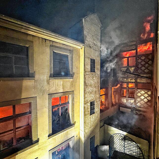 Aus dem hinteren Bereich erkennen die Feuerwehr die wahre Feuersbrunst, die im Inneren der Gebäude wütet.