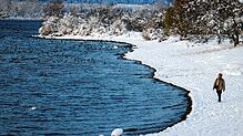 Das Bodenseeufer ist in weiß getaucht. Ein Passant nutzt die frühe Stunde, um im Schnee spazieren zu gehen.