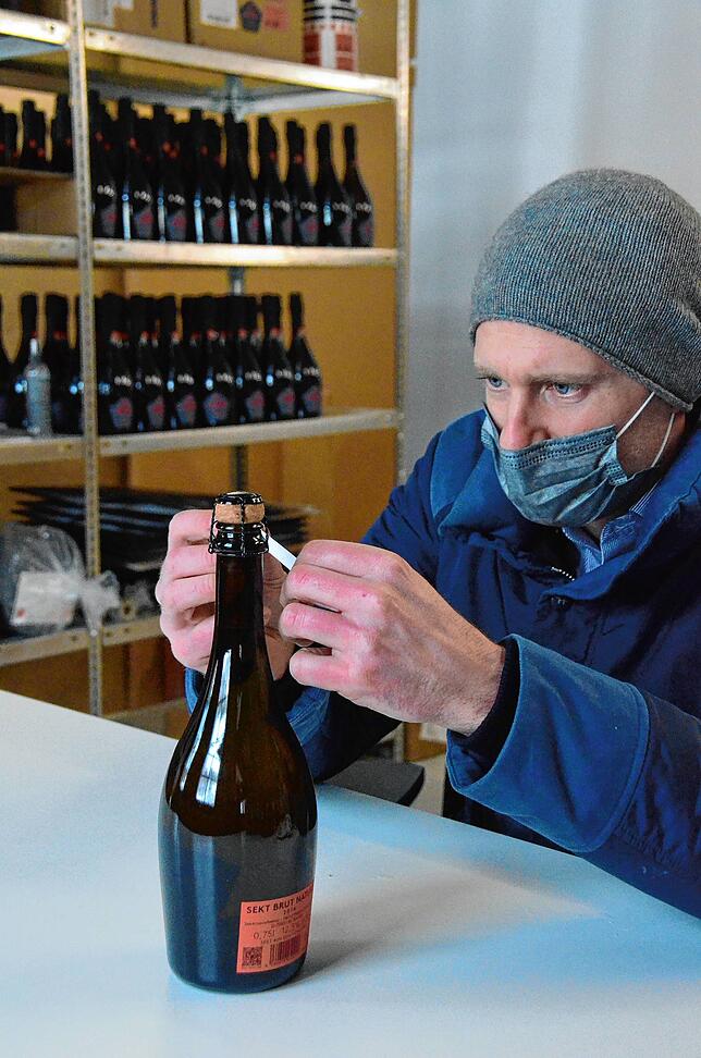 Mit der Hand: Maximilian Wagner klebt ein Etikett auf eine Flasche seiner neuen Sektmarke.