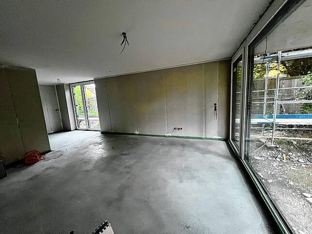 In dieser Zweizimmerwohnung ist bereits der Estrich verlegt, die großen Fenster eingebaut und auch die elektrischen Leitungen verlegt.