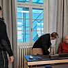 Der Angeklagte im Gerichtssaal mit seinem Verteidiger und einem Justizvollzugsbeamten.