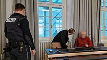 Der Angeklagte im Gerichtssaal mit seinem Verteidiger und einem Justizvollzugsbeamten.