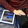Ein Junge der frühkindlichen Autismus hat, sitzt am neben einem Tablet, auf dem der Esel „I-Aah“ aus der Zeichentrickserie „Pu der Bär“ ...
