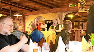 Bürgermeister Gallus Strobel (stehend, links) und Pfarrer Andreas Treuer loben in der „Lilie“ die Paten. Foto:  Hans-Jürgen Kommert