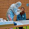 Ein Helfer des DRK nimmt bei einer Frau eine Probe für einen Corona-Schnelltest.