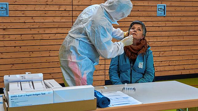 Ein Helfer des DRK nimmt bei einer Frau eine Probe für einen Corona-Schnelltest.