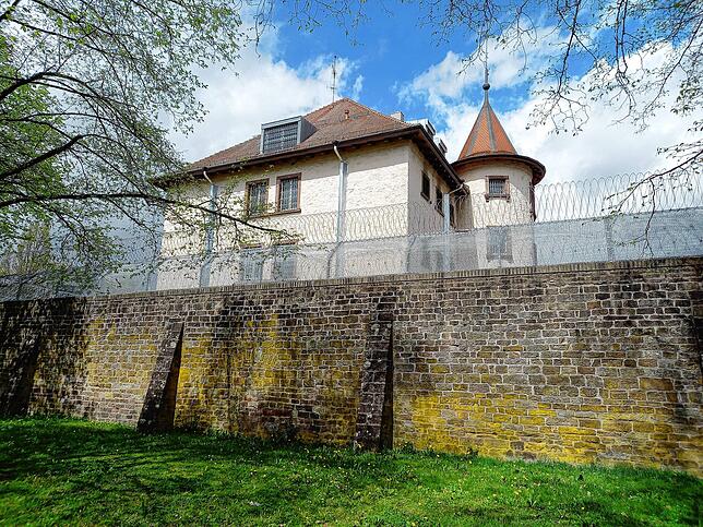 Getrennte Welten: Eine hohe, dicke Mauer mit Stacheldrahtrollen obendrauf schirmt die Justizvollzugsanstalt von der Stadt ab – und die ...