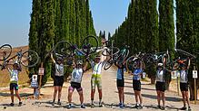 Eine Gruppe der Tour de Lauro auf der Allee zum Bauernhof Poggio Covili im Val d‘Orcia in der Toskana.