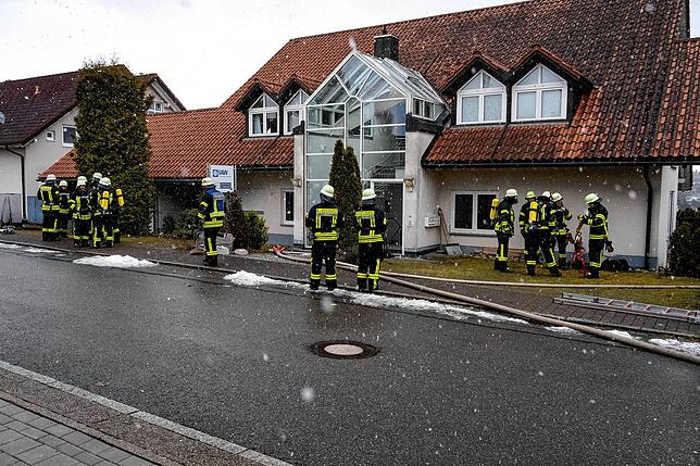 Feuerwehrleute mit Atemschutzausrüstung haben sich vor dem Wohnhaus positioniert.
