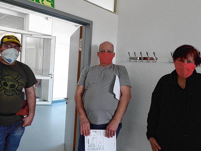 Abstand halten: Drei Mitarbeiter der Behindertenwerkstatt Wallbach zeigen den Nasen-Mundschutz aus Stoff, der vor Ort selbst genäht wurde.