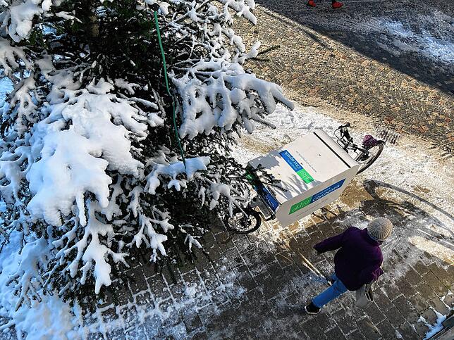 Ein Rad der SÜDKURIER Citylogistik steht bei strahlendem Sonnenschein in der Villinger Bickenstraße unter einem schneebedeckten ...
