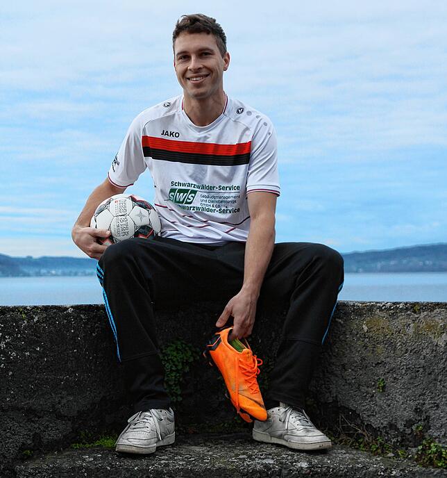 Felix Eiermann sitzt am Bodenseeufer. Er trägt das Trikot, das ihm seine Mitspieler geschenkt haben, in den Händen hält er die ...