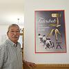 Manfred Flum im Stoll Stuhl Museum neben einem Werbeplakat für den Federdreh, dem ersten gefederten und drehbaren Bürostuhl der Welt, ...