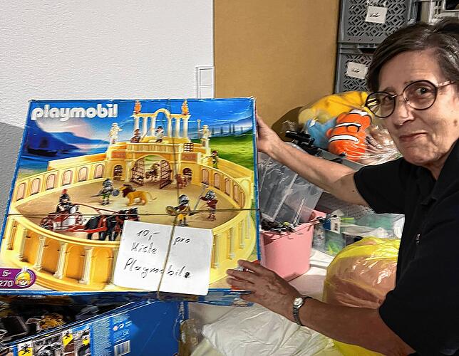 Die Leiterin des Ladens Renate Reinhart zeigt, dass man sogar Playmobilsets im Kleiderladen findet.