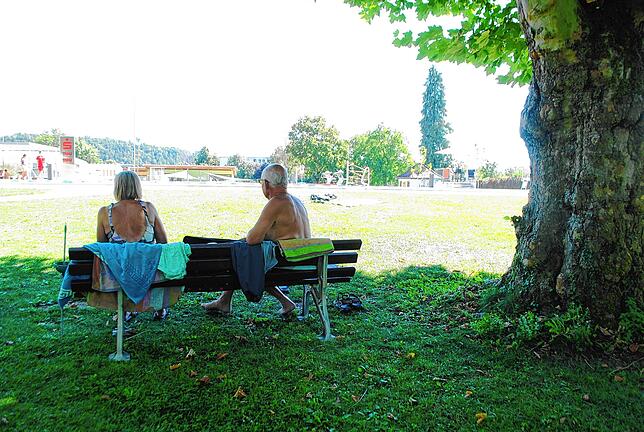 Zwei Badegäste sitzen auf einer Bank im Tiengener Freibad.