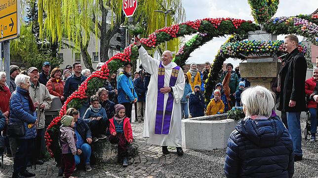Stadtpfarrer Heinz Vogel macht die Segnung des Markelfinger Osterbrunnens 2024 auch für einige der Besucher schwungvoll zu einer nassen ...
