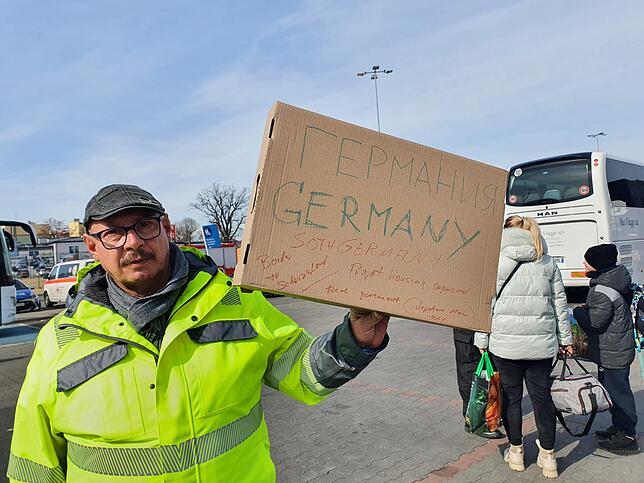 Wolfgang Neumann hält das Schild hoch, mit dem er in der Aufnahmestelle nach Flüchtlingen gesucht hat, die mit nach Radolfzell wollen.