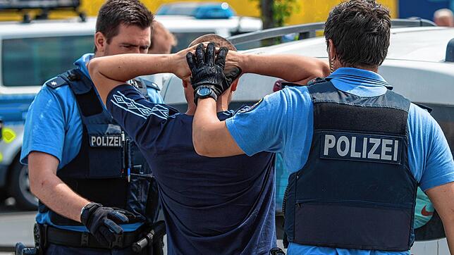 (Symbolfoto) Polizisten durchsuchen einen Mann bei einer Kontrolle auf einem Autobahnparkplatz.