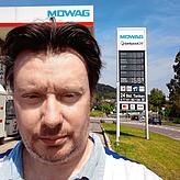 SÜDKURIER-Reporter Gregor Müller steht vor der Preismast der Mowag in Tiengen. Hier kann am günstigsten am Hochrhein getankt werden.