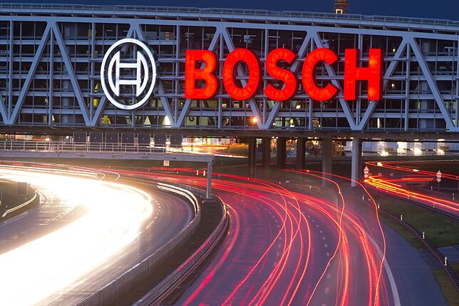 Autos fahren auf der Autobahn A8 unter einer Brücke mit dem Bosch-Logo entlang.