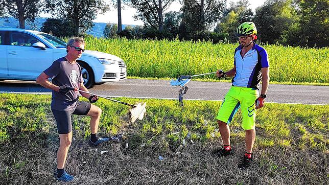 Norbert Wannenmacher (links) und Frank Fischenich sammeln am Straßenrand Müll ein, der beim Mähen geschreddert wurde.