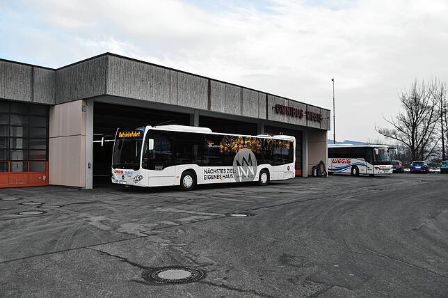 Ein moderner Hybridbus steht für seine nächste Fahrt auf dem Betriebsgelände bereit.