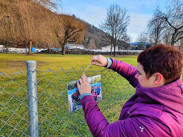 Vorsitzende Christiane Maier befestigt ein Foto am Freibadzaun.