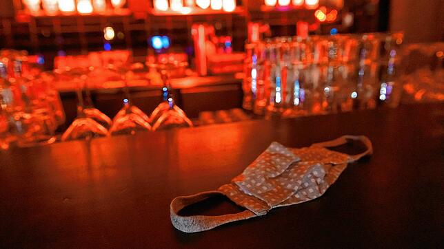 Ein Mund-Nasen-Schutz liegt auf dem Tresen einer Bar (Symbolbild). In den Landkreisen Waldshut und Lörrach ist ab 23 Uhr Sperrstunde in ...