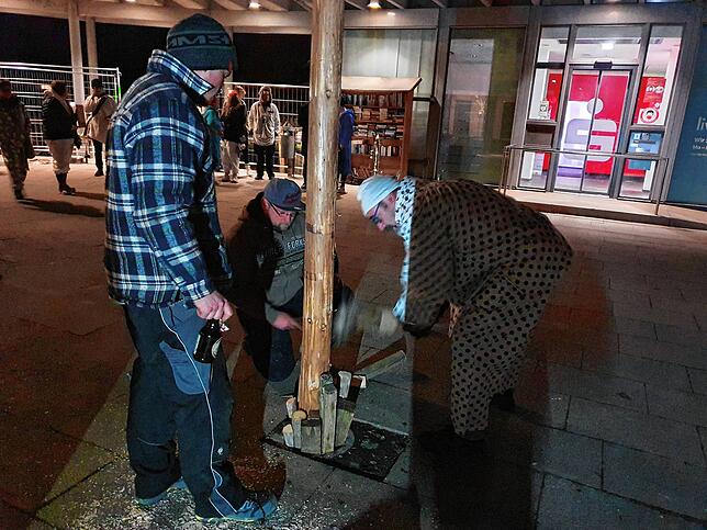 Auf dem Rathausvorplatz klopfen die Männer einen Narrenbaum fest, während hier ein Demozug von Impfkritikern endet.